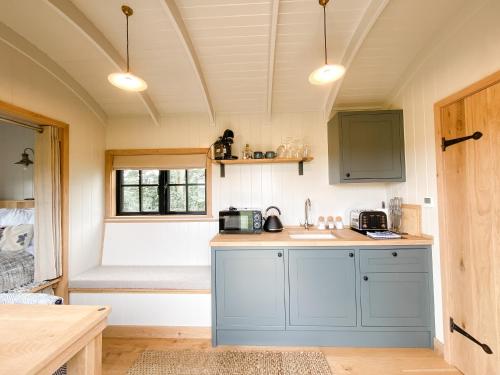 KettonThe Black Swan Shepherd Hut的一间厨房,配有蓝色橱柜和一张位于客房内的床