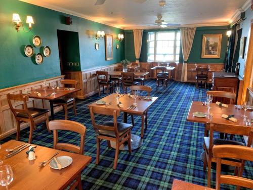 奥本The Manor House Hotel的餐厅设有木桌和椅子,拥有绿色的墙壁