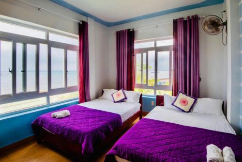 惹岛Thanh Tran Guesthouse Lý Sơn的配有紫色床单和窗户的客房内的两张床