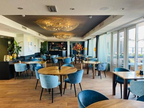 韦斯特-安-斯帕尔8号海滨酒店的餐厅设有木桌、椅子和窗户。