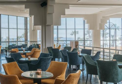 帕福斯St George Beach Hotel & Spa Resort的餐厅设有桌椅和窗户。