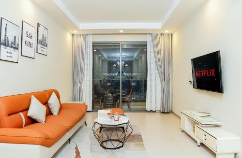 胡志明市Louisa The Gold View Apartment的客厅配有橙色沙发和电视