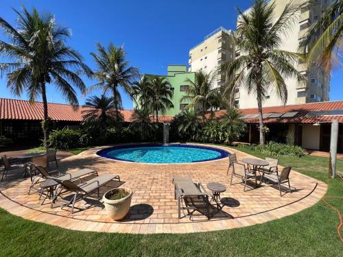 José BonifácioPremier Garden Hotel的一个带桌椅的游泳池,棕榈树