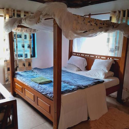 Galumanuastro Breeze Villa的一间卧室配有一张木床和天篷