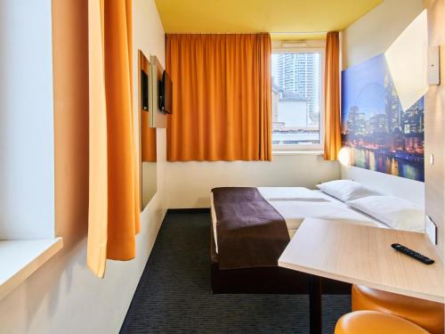 美因河畔法兰克福B&B HOTEL Frankfurt-Hbf的酒店客房设有床、桌子和窗户。