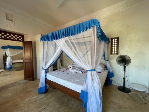 拉穆Swahili Dreams Apartments的一间卧室配有一张蓝色天蓬床