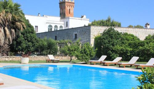 圣维托诺曼玛赛丽亚尹坎特鲁皮酒店的一座带躺椅的游泳池和一座建筑