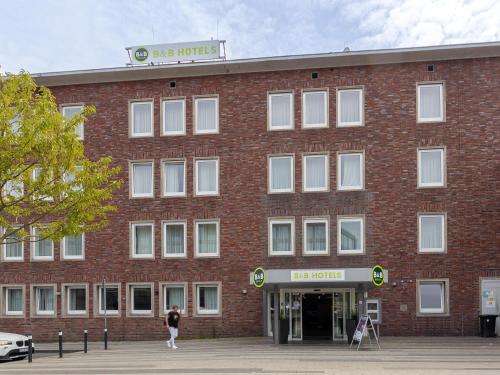 杜伊斯堡B&B Hotel Duisburg Hbf-Nord的一座红砖大楼,外面有女人