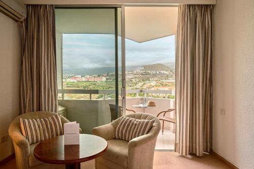 拉克鲁斯Precise Resort Tenerife的客房设有两把椅子、一张桌子和大窗户