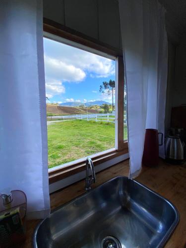 乌鲁比西Casa de temporada - Recanto da invernada的厨房水槽设有窗户,享有田野美景