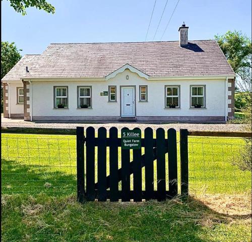 恩尼斯基林Quiet Farm Bungalow Enniskillen Fermanagh的白色房子前面的黑色围栏