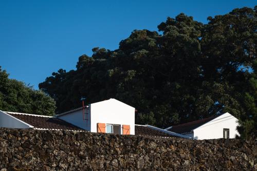 大里贝拉ENTRE MUROS - Turismo Rural - Casa com jardim e acesso direto ao mar的一座白色的房子,在石头墙后面,有树木