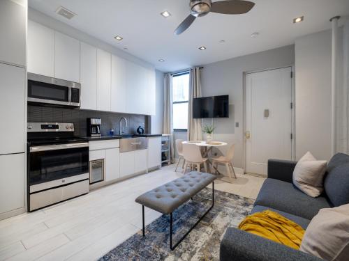 纽约Cozy & Convenient Midtown Apartment!的一间带蓝色沙发的客厅和一间厨房