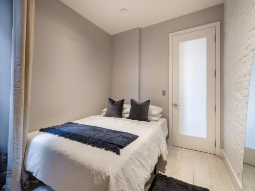 纽约Cozy & Convenient Midtown Apartment!的白色卧室配有带黑色枕头的床
