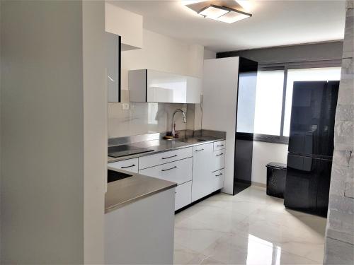 提比里亚4bdrm - 110mr - Dream vacation apartment的厨房配有白色橱柜和黑色冰箱。