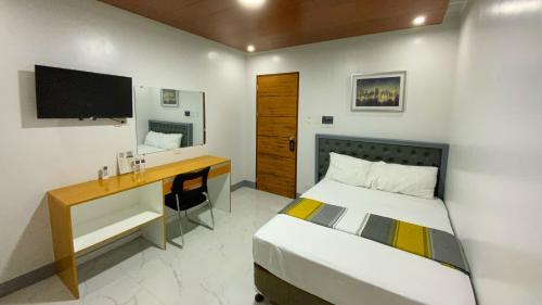 桑托斯将军城ICON Venue and Suites的一间卧室配有一张床、一张书桌和一台电视
