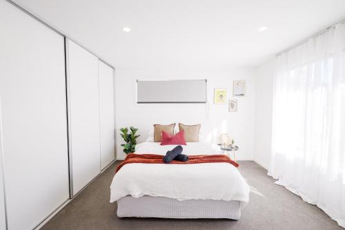 霍巴特Cozy Home Close to Beach and Hobart CBD的白色卧室配有一张带红色枕头的大床