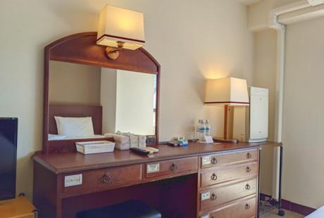 东京泽姆城市旅馆的一间卧室配有带镜子的梳妆台和一张床