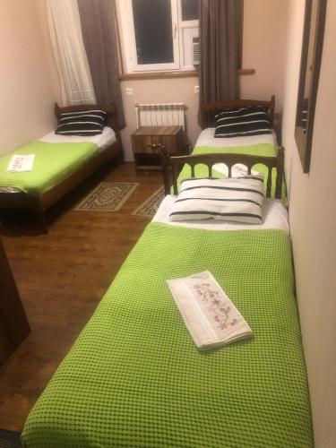 库塔伊西Hotel Nikea Paradiso的配有绿床单的客房内的两张床
