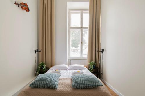 克拉科夫Apartments Studencka Street, Next to Planty Park的一间卧室配有带两个枕头的床和窗户