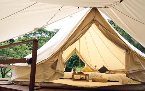 南木曾町ties Camp Ground Nagiso的配有一张床和一张桌子的大型白色帐篷
