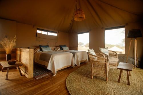 OlmotoniOlkeri Camp的一间帐篷内的卧室,配有两张床和椅子