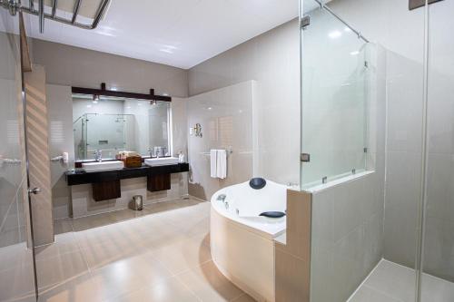 马拉维拉Club Palm Bay的带浴缸和玻璃淋浴间的浴室。