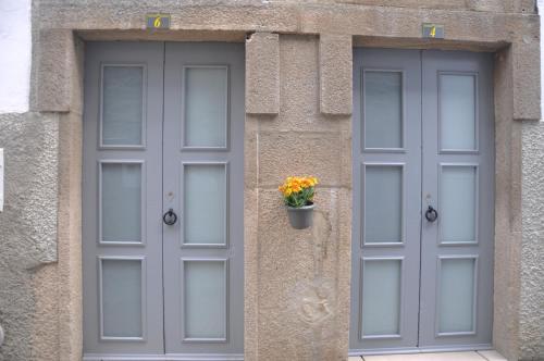 弗雷舒德埃什帕达阿辛塔Casinhas de S. Francisco T2 Azeitona by LovelyStay的两扇灰色门,在建筑物的一侧有花盆