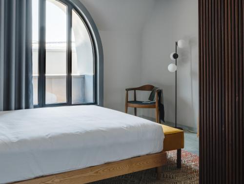 里斯本Lisbon Five Stars Alcântara Lofts的一间卧室设有一张床、一个窗口和一把椅子