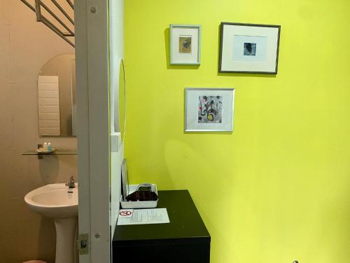 董里诺克胡克旅舍的浴室设有黄色墙壁、水槽和卫生间