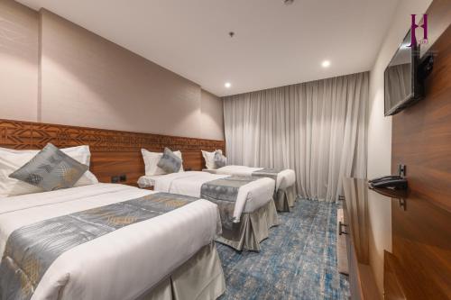 麦加Manazel Al Zaireen Hotel的酒店客房设有两张床和一台平面电视。