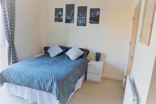 克劳利2BR Apt in Crawley w Parking - Near Gatwick的一间卧室配有一张蓝色床单和两张墙上照片的床。