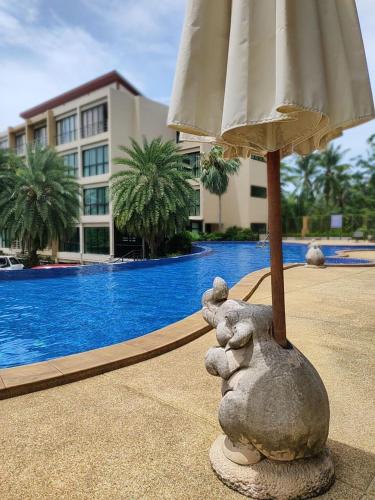 Ban Mae NamApartment的一座石头动物雕像,在游泳池前拿着雨伞