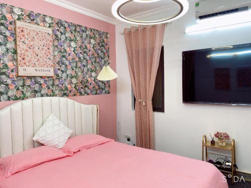 河内FlowerGod Apartments - BlackPink HomeStay的卧室配有粉红色的床和平面电视。