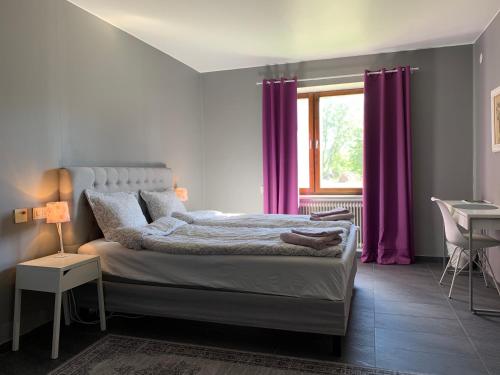上托尔内奥Tornedalens B&B的一间卧室配有一张带紫色窗帘的床和窗户。