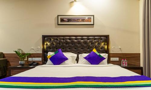 斋浦尔Treebo Tryst Baramasi By Jai Club Prime的一间卧室配有一张大床,提供紫色和黄色枕头