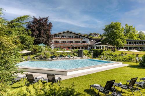 施塔费尔湖畔穆尔瑙穆尔瑙阿尔班霍夫酒店_x000D_的一个带椅子的游泳池和一个背景建筑