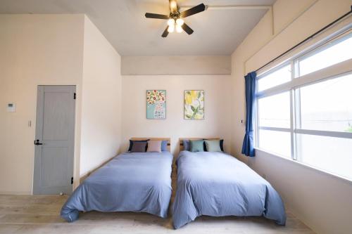 宫古岛Panari的卧室内的两张床,配有吊扇