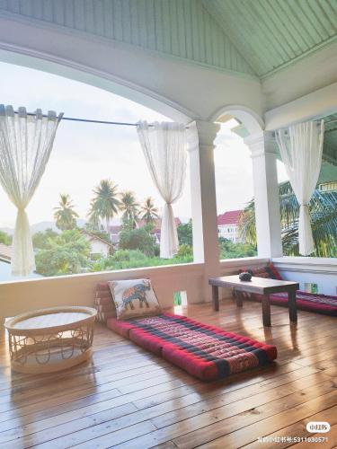 琅勃拉邦天堂鸟花园客栈的带沙发和大窗户的客厅