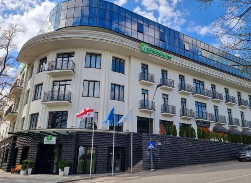 泰拉维Holiday Inn Telavi, an IHG Hotel的前面有旗帜的大型白色建筑