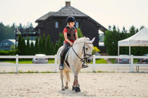 InčukalnsCaravans Camping in Young Riders School的骑白马的年轻女孩