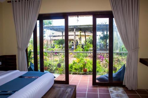 贡布Kampot Eco Village的卧室设有玻璃门,享有花园的景色