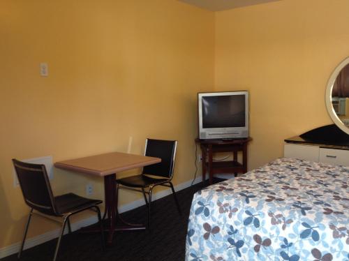 蒙特利尔圣雅克汽车旅馆的一间酒店客房,配有一张床铺、一张桌子和一台电视