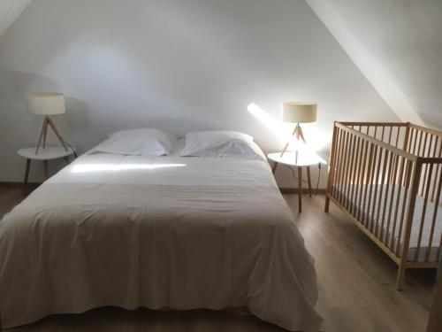 埃斯卡勒Ferme de la Haute-Escalles的卧室配有一张带两盏灯和一张婴儿床的白色床。