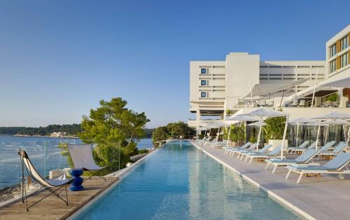 普拉Grand Hotel Brioni Pula, A Radisson Collection Hotel的一座带躺椅的游泳池和一座建筑