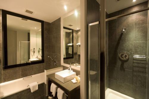 卡迪夫公园广场加的夫酒店的浴室配有盥洗盆、镜子和浴缸