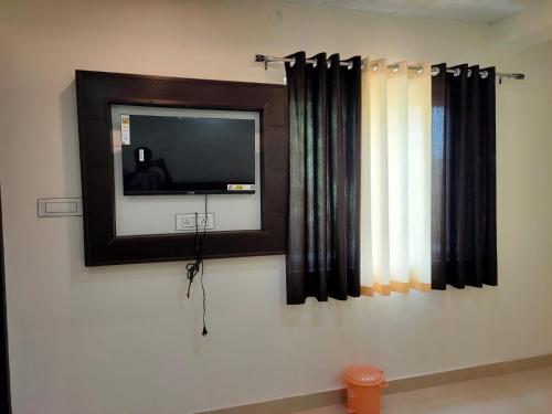 阿格拉Hotel Goyal Palace的墙上的平板电视,带窗帘