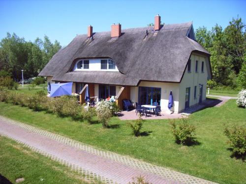 布德明Reetdachhaus Malve 2 mit Kamin für bis zu 6 Personen的茅草屋顶和庭院的房子