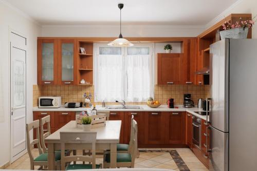 斯达林Beachfront Villa Dionysos - With private beach的厨房配有木制橱柜、桌子和冰箱。