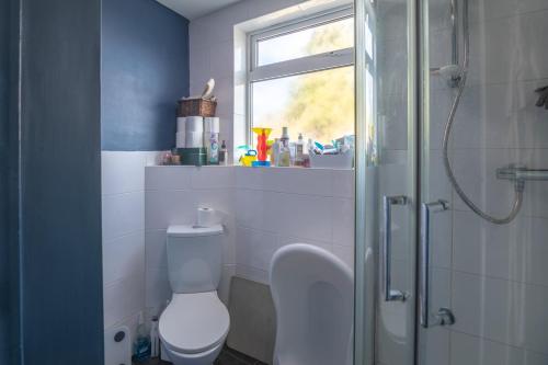 米尔顿凯恩斯Milton Keynes Cosy Guest House的一间带卫生间和淋浴的浴室以及窗户。